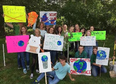 Cheerful students holding up signs in protest of climate change.